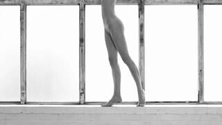 Nude, filmed from the neck down, in black and white