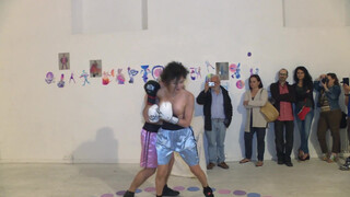 4. Topless woman spars with a male boxer in “PAOLO BIELLI (RING) VIOLET-RING”