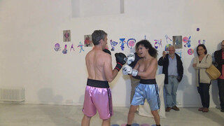 5. Topless woman spars with a male boxer in “PAOLO BIELLI (RING) VIOLET-RING”