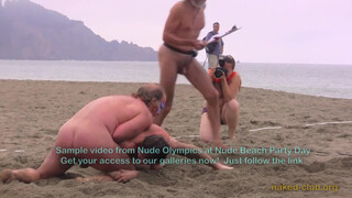 5. Two naked guys are “Wrestling clothing-free at a beach festival”. Also, topless photographer’s boobs are visible in the background