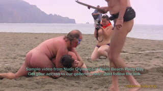 7. Two naked guys are “Wrestling clothing-free at a beach festival”. Also, topless photographer’s boobs are visible in the background