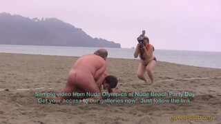 3. Two naked guys are “Wrestling clothing-free at a beach festival”. Also, topless photographer’s boobs are visible in the background